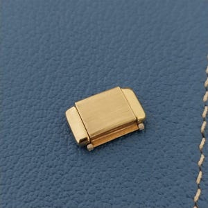 May include: Gold-toned watch band link with a brushed finish.