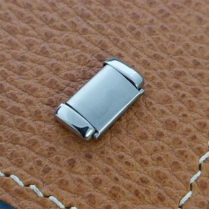 May include: A silver metal watch band clasp. The clasp is rectangular with rounded edges and a brushed finish.