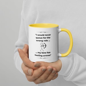 Puede incluir: Taza de cerámica blanca con borde y asa amarillos. La taza presenta una ilustración en blanco y negro de un figurín con un arco y una flecha. El texto en la taza dice "Nunca haría cola para el papel equivocado... mi arco tiene flechas curativas".