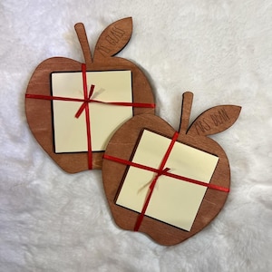 May include: Two wooden apple-shaped notepads with red ribbon. The top notepad says "Mrs. Glass" and the bottom notepad says "Mrs. Dean".
