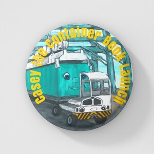 May include: A yellow button with the text "Casey the Container Book Launch" around a cartoon illustration of a blue container truck and a white tugger truck.