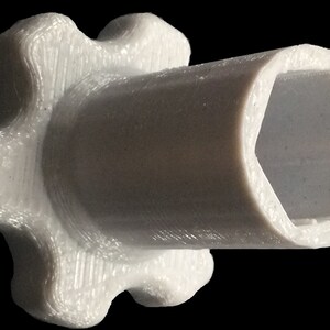Pu&ograve; includere: Un adattatore bianco in plastica stampato in 3D con un'apertura esagonale e un bordo esterno a forma di stella.