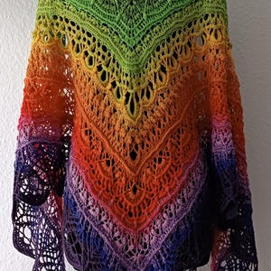 May include: A rainbow ombre crochet shawl with a lacy pattern. The shawl is displayed on a mannequin.