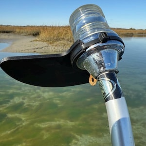 May include: A silver and black boat navigation light with a clear glass lens. The light is mounted on a silver pole and has a black plastic shield.