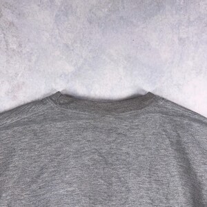 May include: A heather gray crew neck sweatshirt. The neckline is ribbed and the body of the shirt is a solid gray color. The fabric appears to be a soft, comfortable material.