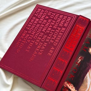 May include: A red hardcover book with the title "Dracula" by Bram Stoker. The book cover features a portrait of a woman in a white dress with a red background.