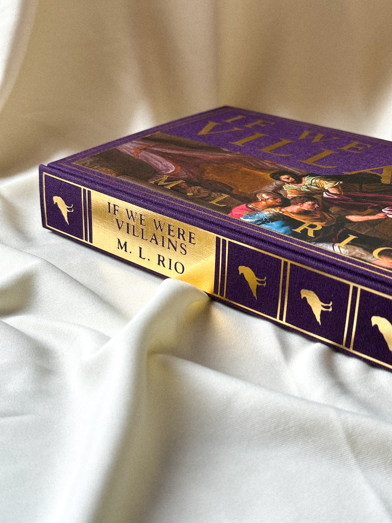 May include: A purple hardback book with gold lettering that reads "If We Were Villains" by M.L. Rio. The book cover features a painting of a group of people in a dramatic scene.