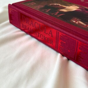 May include: A red hardcover book with the title "Dracula" by Bram Stoker on the spine.