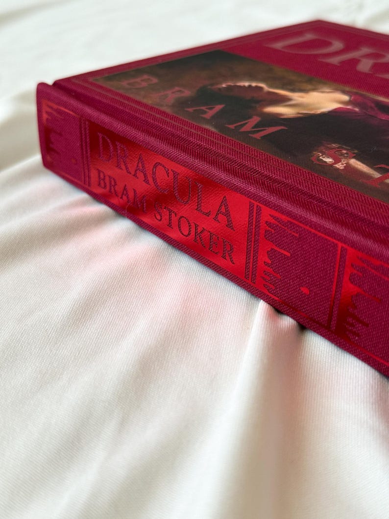 May include: A red hardcover book with the title "Dracula" by Bram Stoker on the spine.