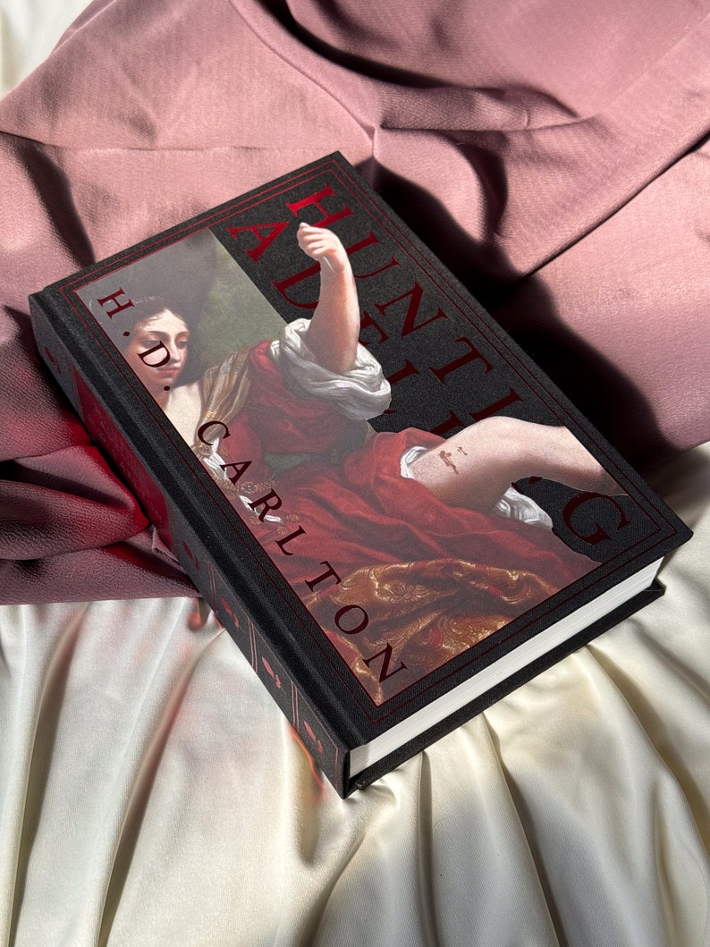 Puede incluir: Un libro de tapa dura negro con el t&iacute;tulo "A Hunting Adieu" en letras rojas. La portada del libro presenta una pintura de una mujer con un vestido rojo y un brazo levantado.