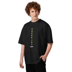 Puede incluir: Camiseta negra de gran tamaño con el texto "ERROR 404" en letras verticales de color verde neón. La camiseta tiene cuello redondo y mangas cortas. El texto "DISCIPLES DISTILLED" está debajo.