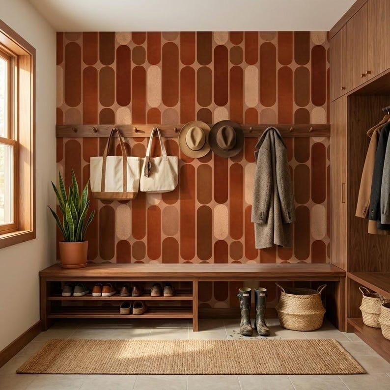 a well-organized entryway with a wooden bench, a shelf for shoes, and a wall with a patterned orange and brown design. There are two handbags hanging on the wall, and a plant is placed on the floor next to the bench.