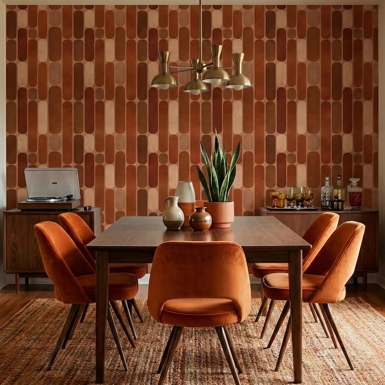 a modern dining room with a wooden table surrounded by orange upholstered chairs. The walls are covered in a patterned wallpaper, and a chandelier hangs above the table. The room also features a record player and a potted plant, adding to the vintage-inspired ambiance.