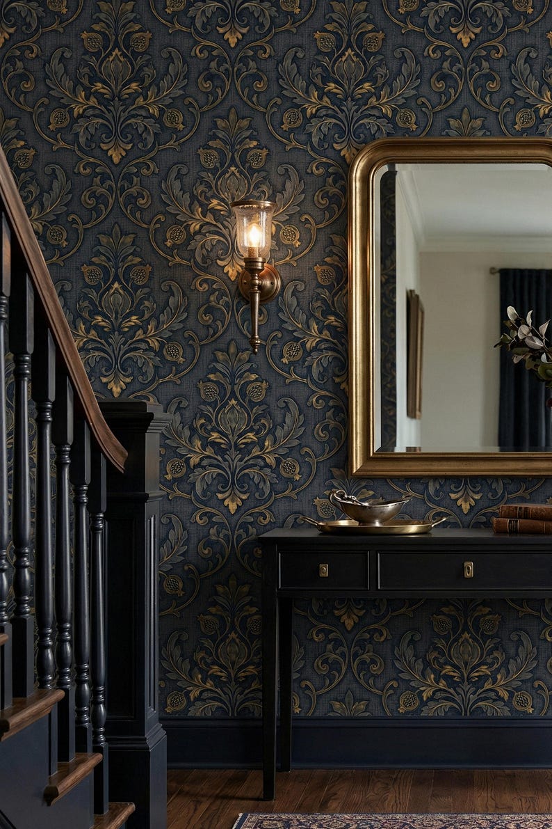 May include: Interior shot featuring a navy blue and gold damask wallpaper. A gold-framed mirror and a black console table with a brass sconce and a staircase are visible. The wallpaper has a repeating floral pattern.