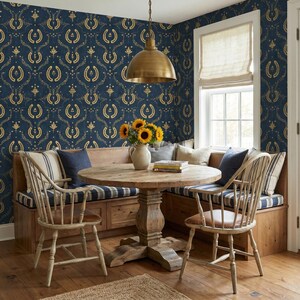 a cozy dining area with a round wooden table, two white chairs, and a bench with a vase of sunflowers. The walls are covered in a blue and gold patterned wallpaper, and a window with a white shade is visible. The room has a warm and inviting atmosphere.