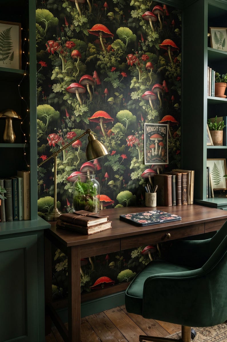 K&ouml;nnte beinhalten: Ein gem&uuml;tliches Heimb&uuml;ro mit einem dunklen Holzschreibtisch, einem gr&uuml;nen Samtstuhl und einer Tapete mit Pilzmotiven. Eine Messing-Schreibtischlampe beleuchtet ein Terrarium und B&uuml;cher. Ein gerahmter Druck und ein Poster mit dem Text "MIDNIGHT FUNGI" sind ebenfalls zu sehen.