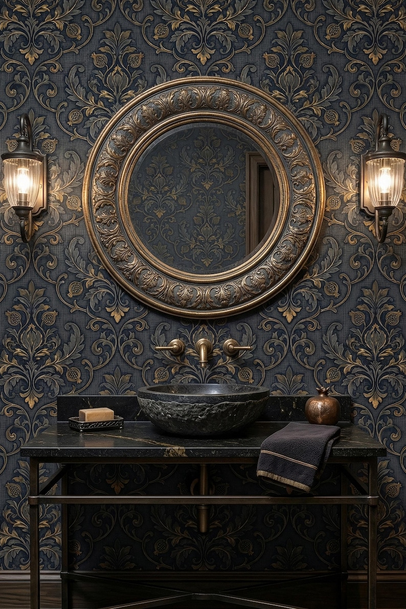 May include: A luxurious bathroom vanity with a dark granite countertop, a textured stone sink, and a large round mirror with a gold frame. The wallpaper features a dark blue and gold floral pattern. Two sconces flank the mirror.