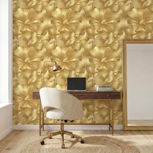 a modern and stylish workspace with a wooden desk, a white chair, and a gold-framed mirror on the wall. The wall is covered in a gold floral wallpaper, creating a luxurious and sophisticated atmosphere.