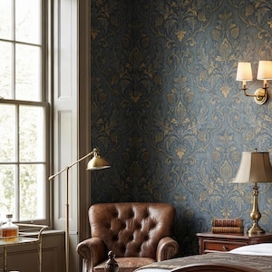 May include: A luxurious bedroom with dark blue wallpaper featuring a gold floral pattern. A tufted brown leather armchair sits near a window. A brass floor lamp and a bedside table with a lamp and books complete the elegant decor.