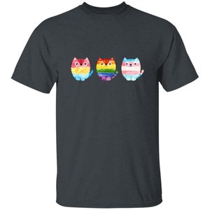 Puede incluir: Una camiseta azul oscuro con tres gatos de dibujos animados que llevan colores arcoíris. Los gatos están dispuestos en fila de izquierda a derecha.