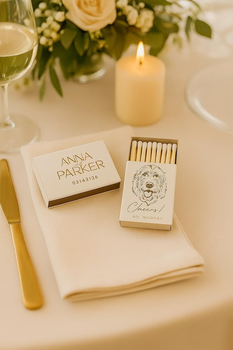 May include: A wedding table setting with a lit candle, floral arrangement, and a gold knife. Two matchboxes are visible, one with the text "Anna & Parker" and the other with a dog illustration and the word "Cheers!"