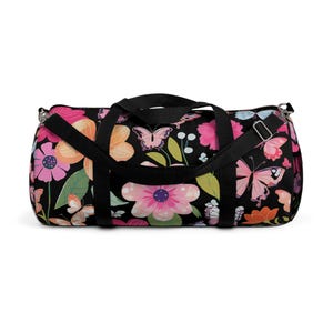 Bolsa esportiva floral colorida com fundo preto, feita de poliéster leve, com alça ajustável, ideal para academia ou viagens.