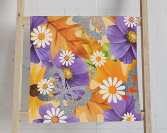 May include: A decorative towel featuring a floral pattern with purple, yellow, and orange flowers, along with brown leaves and a silver glitter butterfly design. The towel is hanging on a wooden ladder, showcasing a vibrant and colorful design.