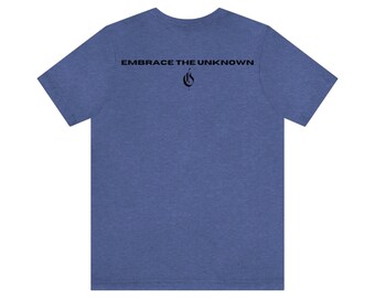 Op de afbeelding: Een blauw heather t-shirt met de tekst "Embrace the Unknown" gedrukt op de achterkant. Een gestileerde vlamgrafiek bevindt zich onder de tekst.