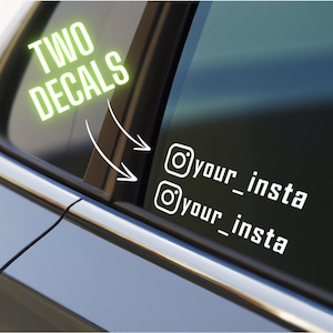 May include: A white ceramic mug with a black handle and the text "But First, Coffee" in a bold, black font. The mug is filled with a dark liquid, likely coffee, and sits on a light-colored surface.