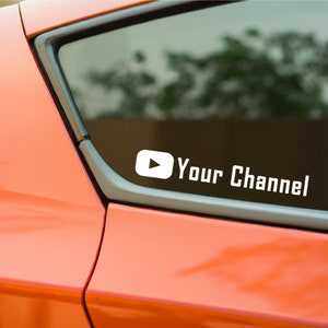 May include: White vinyl sticker with a red play button and the text "Your Channel" on a red car.