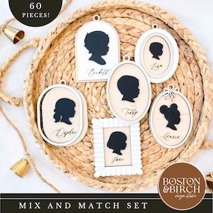 Peut inclure: Un ensemble de six ornements en silhouette en bois avec des profils noirs et des cadres blancs. Chaque ornement présente le profil et le nom d'un enfant différent. L'ensemble est présenté sur un plateau tressé. Le texte "60 PIECES!" est en haut.