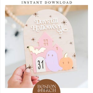 May include: Wooden Halloween countdown sign with a pink house, a purple ghost, and an orange pumpkin. The sign reads "Days till Halloween" and displays the number "31". Decorative gold stars and a gold bat are also featured.