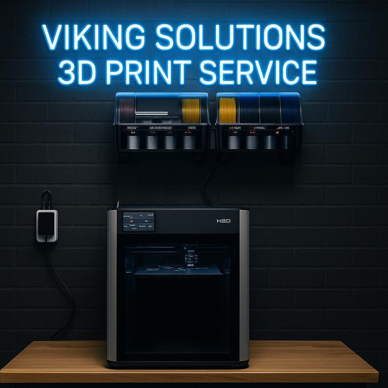 K&ouml;nnte beinhalten: Ein 3D-Drucker mit dem Text "VIKING SOLUTIONS 3D PRINT SERVICE" in Neonblau. Der Drucker ist schwarz und silber, mit einem Display. &Uuml;ber dem Drucker befinden sich Spulen mit Filament in verschiedenen Farben. Der Hintergrund ist eine dunkle Backsteinmauer.