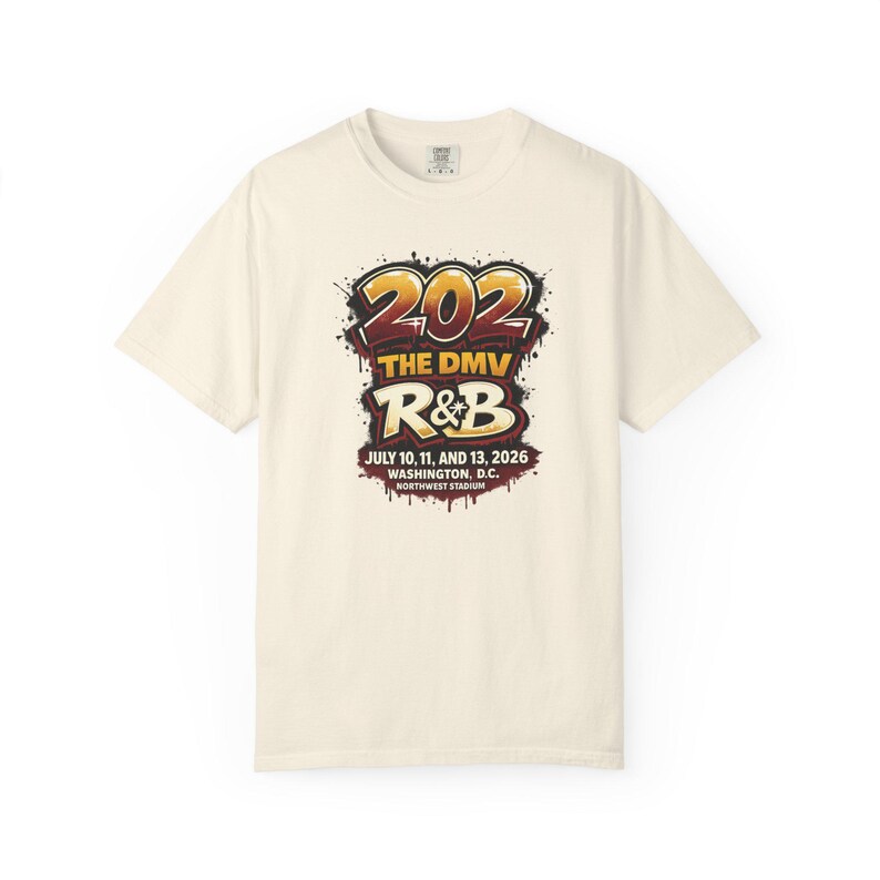 May include: A cream-colored short-sleeve t-shirt featuring a graphic with the text 202 THE DMV R&B JULY 10, 11, AND 13, 2026 WASHINGTON, D.C. NORTHWEST STADIUM in a stylized, graffiti-inspired font with red, yellow, and black paint splatter.