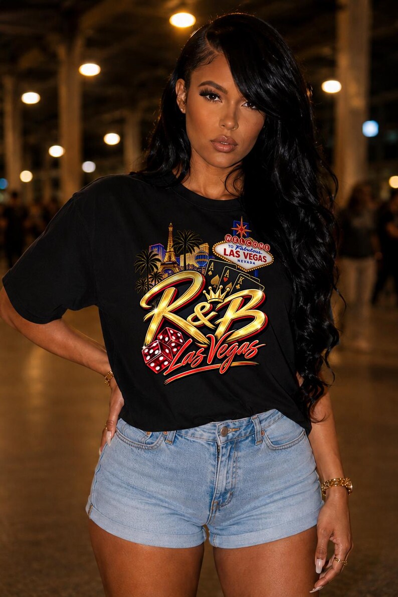 Pu&ograve; includere: Una t-shirt nera a maniche corte con una stampa grafica che include il testo R&B Las Vegas, un cartello Welcome to Fabulous Las Vegas, carte da gioco, dadi, una corona e palme, abbinata a pantaloncini di jeans azzurri con orlo risvoltato.