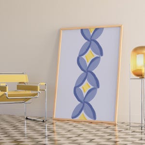 May include: A framed print featuring an abstract floral design in shades of blue and yellow. The print is displayed against a white wall in a room with a yellow chair and a gold floor lamp.