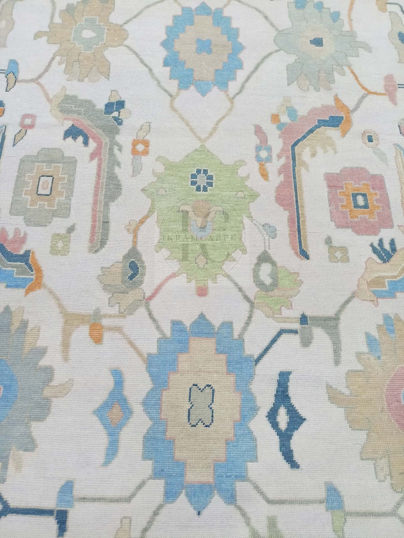 May include: A white rug with a repeating pattern of blue, green, and pink floral designs. The rug has a woven texture and a subtle sheen.