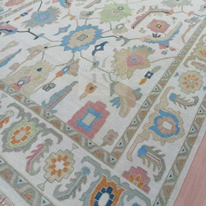 May include: A white rug with a traditional Persian design. The rug features a central medallion with floral motifs and geometric patterns in shades of blue, pink, orange, and green.