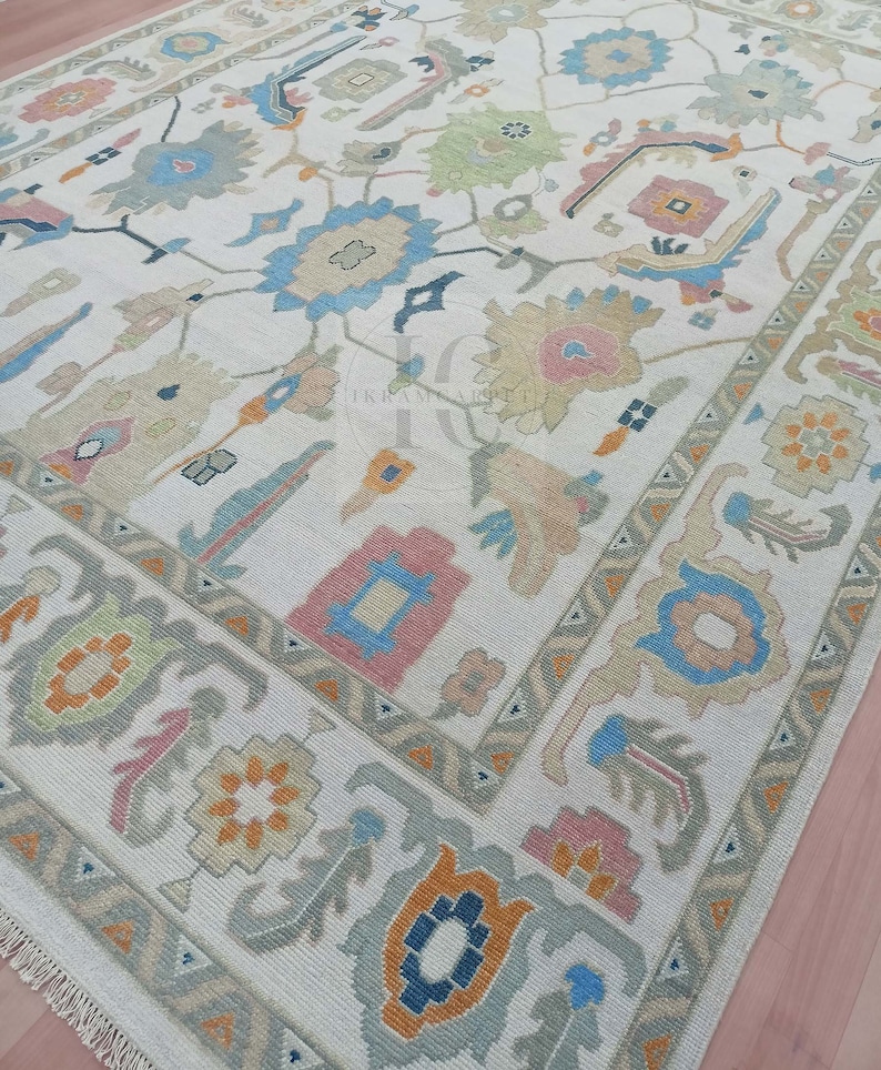 May include: A white rug with a traditional Persian design. The rug features a central medallion with floral motifs and geometric patterns in shades of blue, pink, orange, and green.