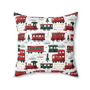 May include: Square throw pillow with a repeating pattern of red trains, green train cars, trees, clouds, and arrows on a white background. The pillow has a solid white back.