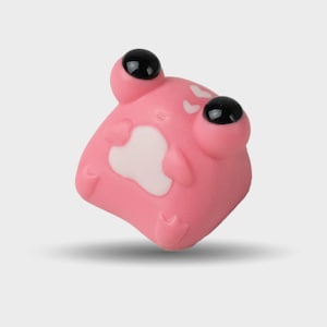 May include: A pink frog-shaped ornament with large, black eyes and a white belly patch. The figurine has a smooth texture and is designed with rounded features, giving it a playful appearance. The frog is a whimsical decorative item.