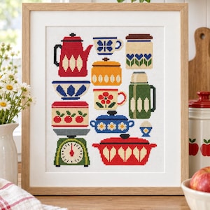 May include: A framed cross-stitch embroidery featuring a collection of colorful kitchenware, including a red teapot, a green kitchen scale, various patterned bowls, mugs, a thermos, and lidded pots, all arranged on a white fabric background.