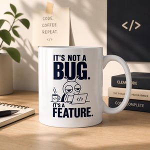 Op de afbeelding: Witte keramische mok met de tekst "IT'S NOT A BUG. IT'S A FEATURE." en een cartoon bug-personage dat een laptop gebruikt. De mok heeft ook een koffiekopje met codesymbolen.