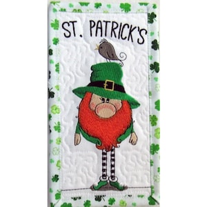 May include: Embroidered St. Patrick's Day wall hanging featuring a cartoon leprechaun with a green hat and red beard. The text "ST. PATRICK'S" is at the top. The border is decorated with green shamrocks.