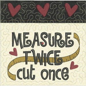 May include: A beige fabric square with a black embroidered saying "Measure twice cut once" with a brown measuring tape and red hearts.