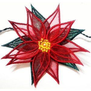 May include: A red poinsettia flower with green leaves, embroidered with a sparkly yellow center.