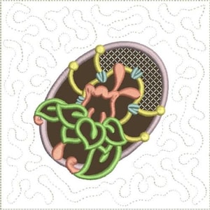 May include: A brown oval-shaped embroidery design with a floral motif. The design features a pink flower with green leaves and a yellow and blue patterned background.