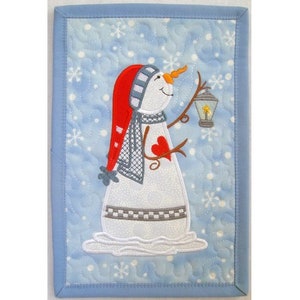 Pode incluir: Um boneco de neve com um chapéu vermelho, um cachecol cinzento e um coração vermelho no peito segura uma lanterna com uma vela acesa dentro. O boneco de neve está em pé sobre um fundo azul com flocos de neve brancos.