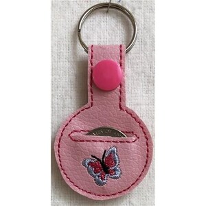 May include: Pink leather keychain with a round coin pocket and a butterfly design. The keychain has a silver key ring and a pink button.