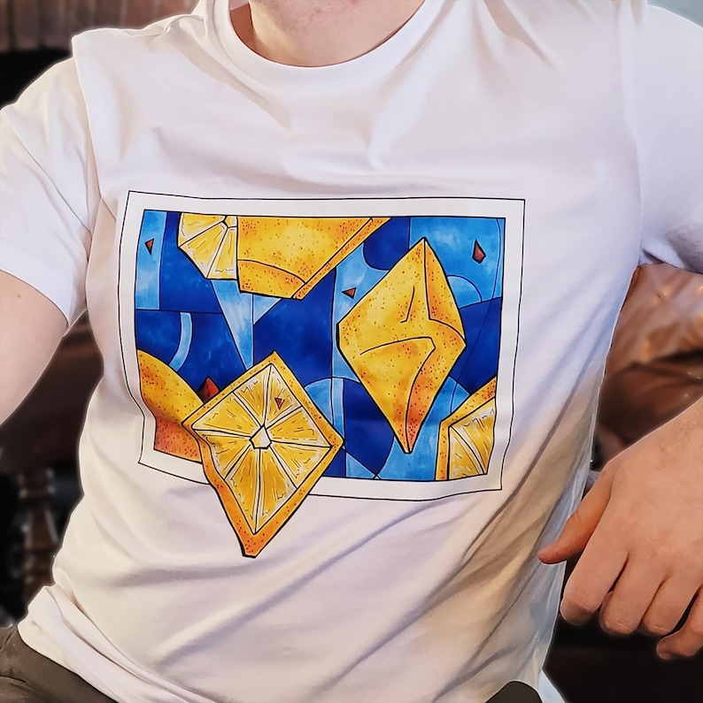 May include: White t-shirt featuring a vibrant graphic design. The design showcases yellow geometric shapes against a blue background, with red accents. The artwork is framed within a black border, creating a modern and eye-catching aesthetic.